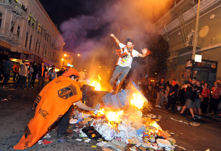 FOTO ABRE A man jumps over a pile of burning trash in San Francisco's Mission district::AFP PHOTO:JOSH EDELSON