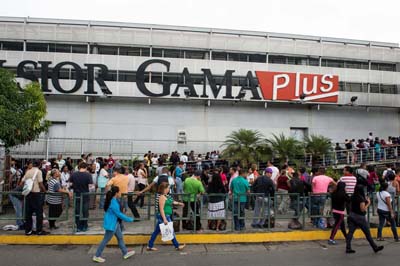 People queue up outside a supermarket in Caracas on January 13, 2015. Venezuela suffers a shortage of almost a third of commodities, inflation of 64% in 2014 and an economic recession caused in part by drought currency since 2013 is limiting essential imports. AFP PHOTO/FEDERICO PARRA