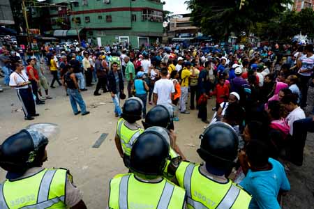 Efectivos de la Policía Nacional Bolivariana resguardan a la gente que protestó por la falta de comida este sábado en Catia AFP / Federico Parra