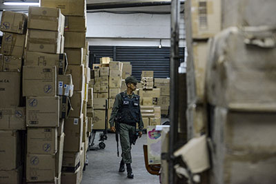 A member of the Venezuelan national guard walks between boxes full of confiscated toys in a warehouse in Caracas on December 9, 2016.  The Venezuelan government seized 3.8 million toys on December 9, 2016 from one of the country's main distributors - which it accuses of hoarding - to sell them at lower prices in poor neighborhoods. / AFP PHOTO / FEDERICO PARRA